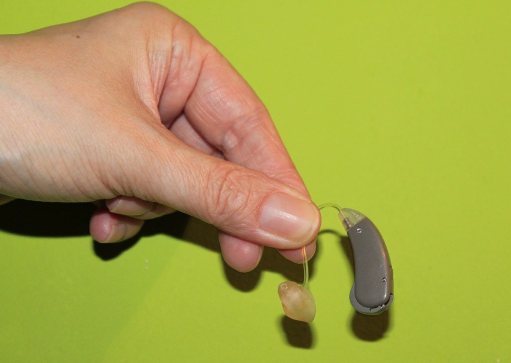 aparat słuchowy trzymany w ręce